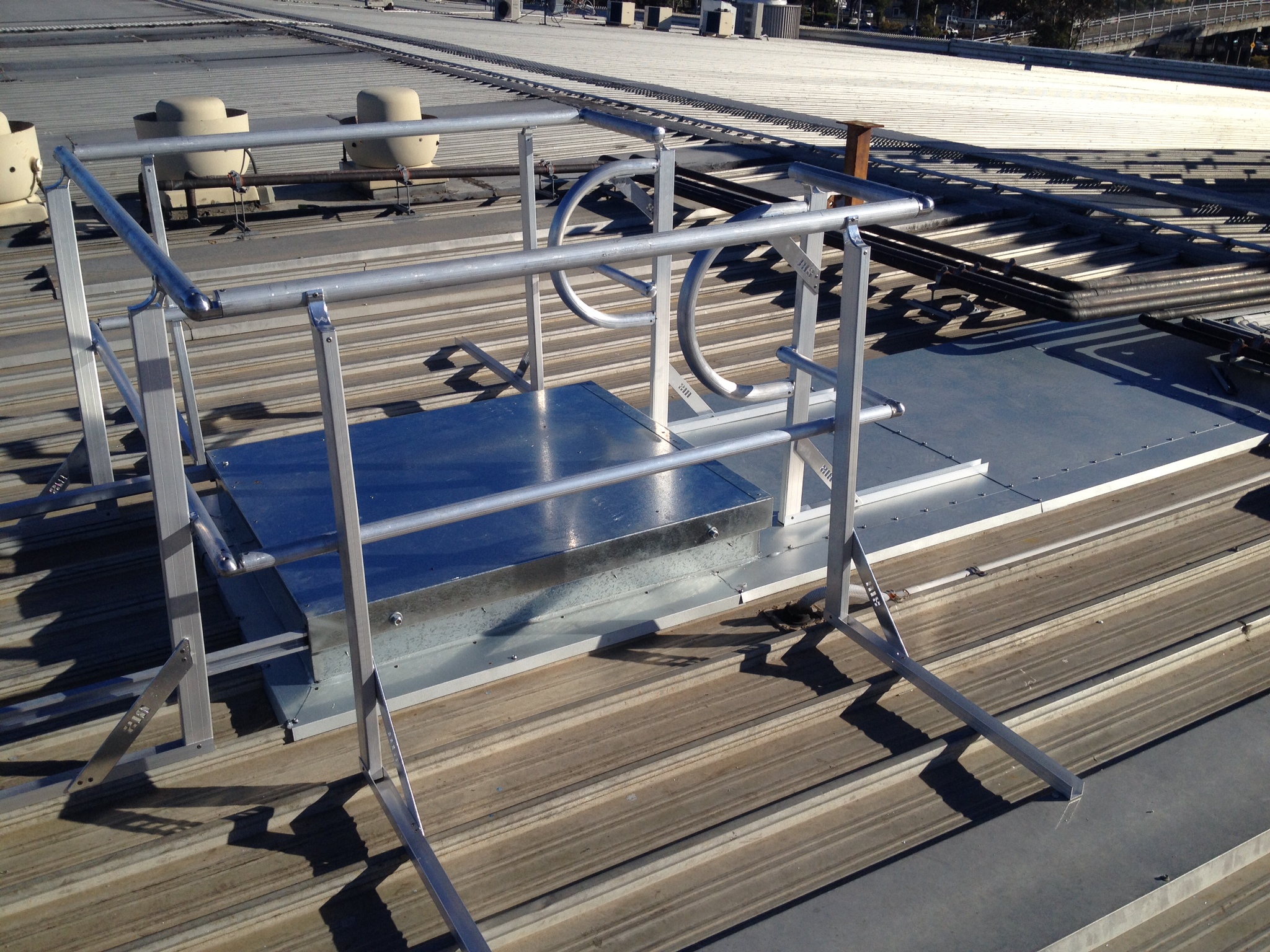 Roof hatch surrounded by a guardrail system on a metal roofing structure, illustrating RISSafety's safety access solutions for working at heights.
