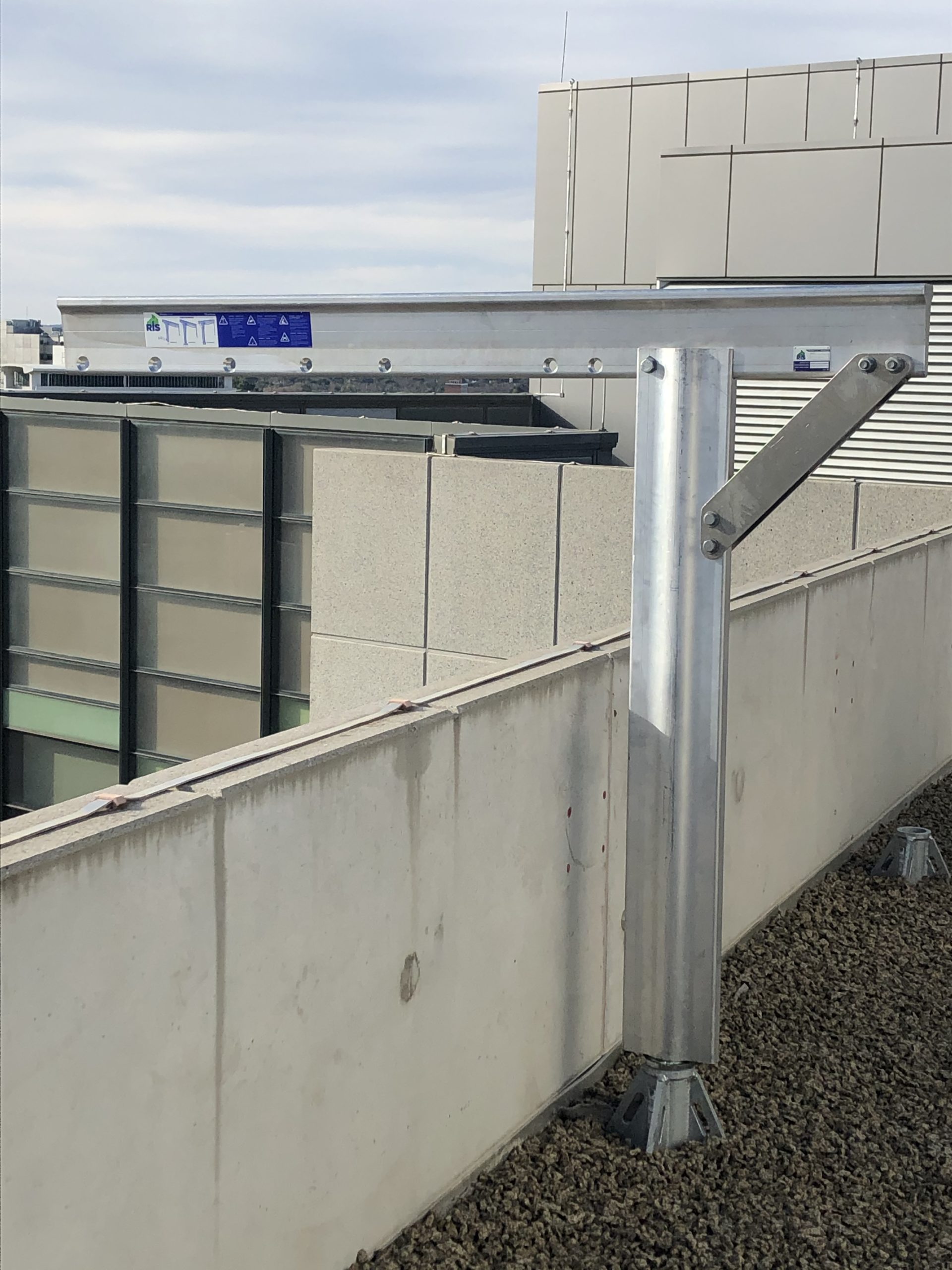 Davit arm safety system mounted on a rooftop, showcasing installation for fall prevention in high-rise buildings, with visible safety labels and structural supports.