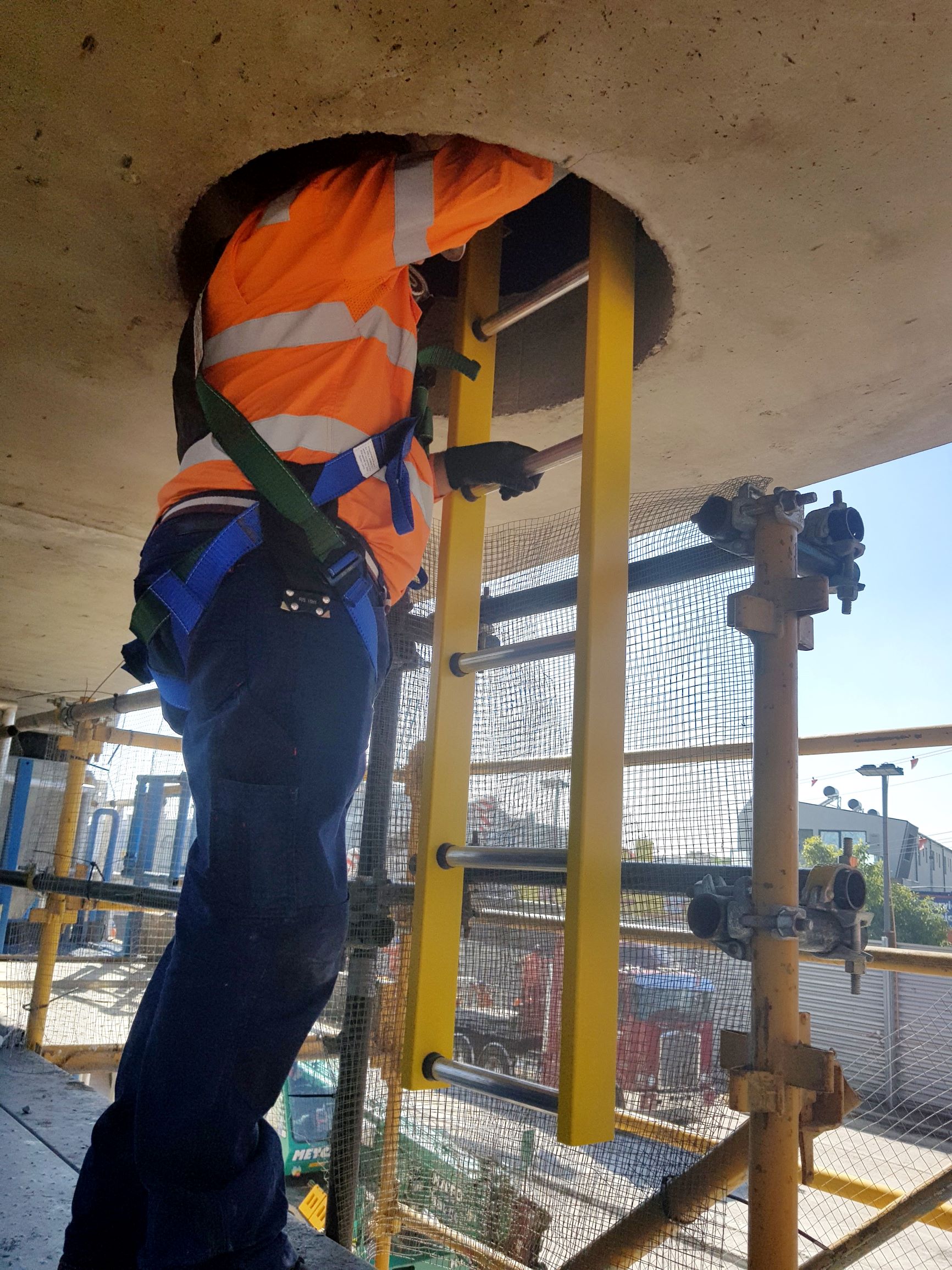 Dandenong railway line construction, worker at height using safety equipment and access ladder.