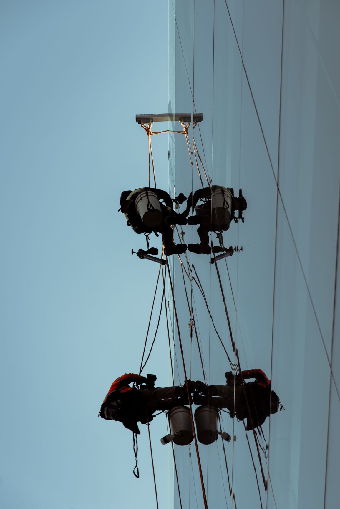 Man working at height with safety harness and equipment, illustrating workplace safety protocols.