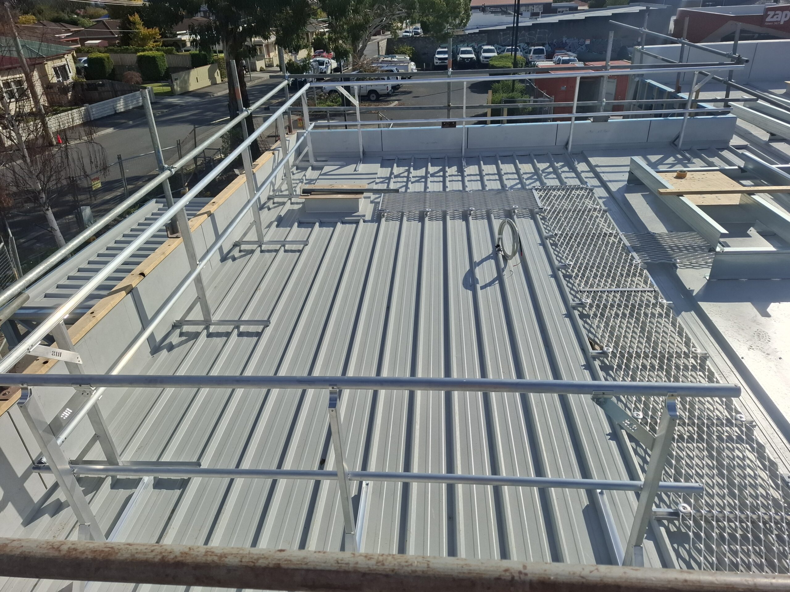 Roof safety system installation featuring metal guardrails and access points, emphasising RISSafety's height safety solutions for construction sites.